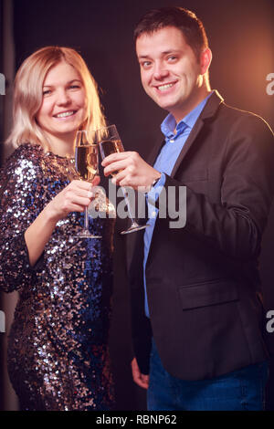 Photo of happy woman in brilliant dress and men with wine glasses with champagne on black background Stock Photo