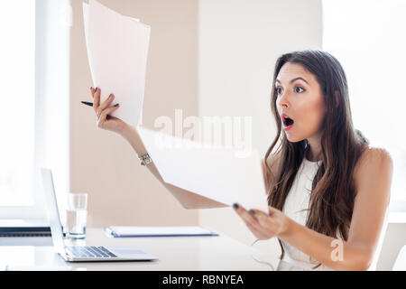 Shocked businesswoman reading paper at workplace in office. Business woman frustrated and stressed with new contract Stock Photo