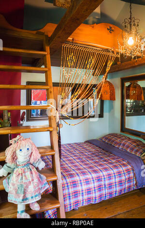 Ragdoll sitting on wooden bunkbed ladder in child's bedroom on the upstairs floor inside an old circa 1850 Canadiana cottage style home Stock Photo