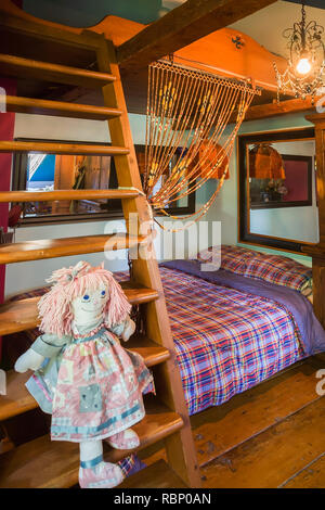 Ragdoll sitting on wooden bunkbed ladder in child's bedroom on the upstairs floor inside an old circa 1850 Canadiana cottage style home Stock Photo