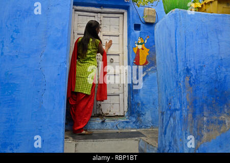 woman knocking door of blue house, Jodhpur, Rajasthan, India, Asia Stock Photo