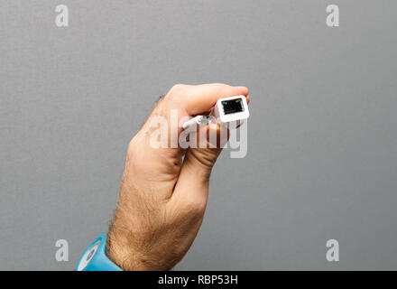 Man holding against gray background a new cable from with USB-C to  Adapter to ethernet internet cable  Stock Photo
