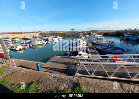 The small high water harbour at Porthcawl with many small and medium sized boats moored in a safe place by the town and beaches on a sunny winters day Stock Photo