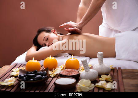 Therapist's Hand Giving Back Massage To Relaxed Young Woman In Spa Stock Photo
