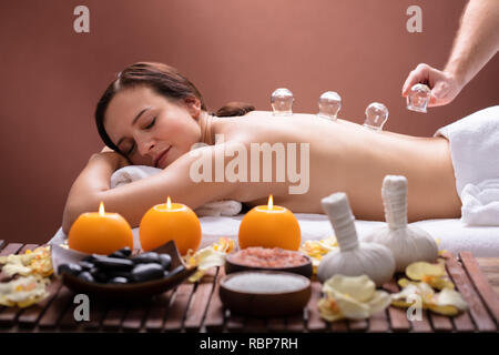 Relaxed Young Woman Receiving Cupping Treatment On Her Back In Spa Stock Photo