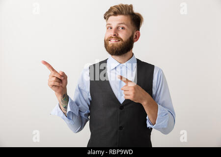 Image of a handsome young bearded man standing isolated over white wall background pointing. Stock Photo