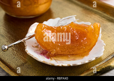 Piece of home-made orange spoon sweet and full jar on vintage bronze tray. Stock Photo