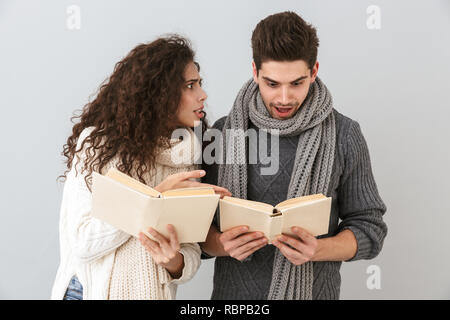 Image of smiling couple man and woman reading books together isolated over gray background Stock Photo
