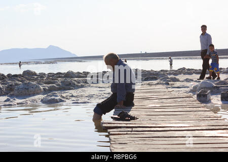 An old man sitting on the beach of salt Urmia Lake, West Azerbaijan province, Iran Stock Photo