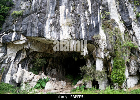 Beautiful natural limestone cave entrance in Malaysia. Limestone Hill and Cave.Jungle covered and dramatic rounded hill and huge hollow feature- Image Stock Photo