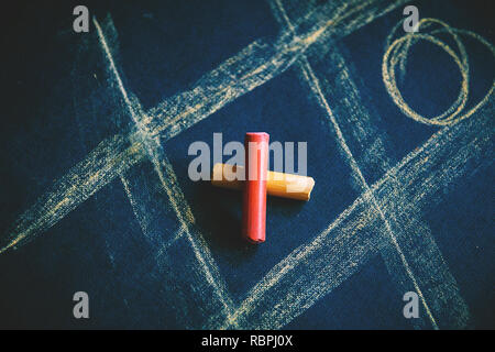 cross zero of colored crayons and toe painted on dark background. Stock Photo