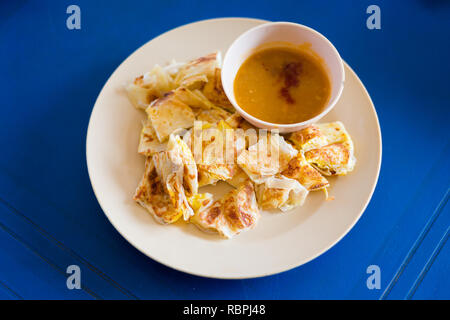 Fresh prepared Malaysian roti telur with egg served with lentil dahl in local restaurant on Langkawi island. Traditional asian cuisine made of fresh i Stock Photo