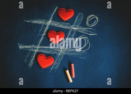 cross zero of hearts and colored crayons on dark background. Stock Photo