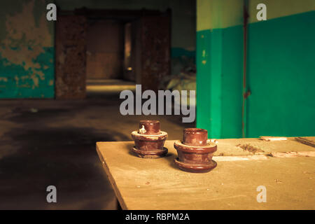 Electrical insulator on table inside abandoned old factory building. Stock Photo