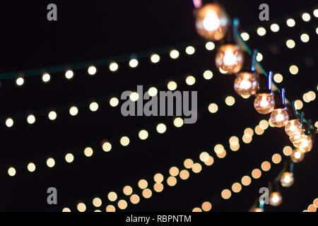 Strings of lights contrasted against a black sky at a festival Stock Photo