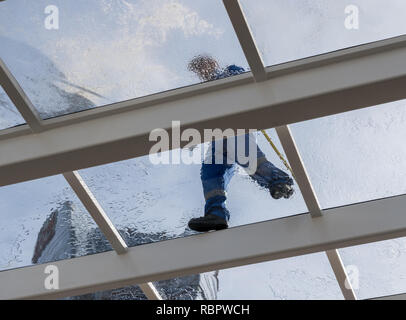 Worker cleaning large glass roof over swimming pool Stock Photo