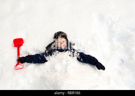 Winter day, a lot of snow, the child buried himself with a children's shovel around the neck in the snow. Stock Photo