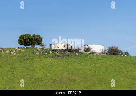 Large, round water tanks on top of a hill on a blue sky background, California Stock Photo