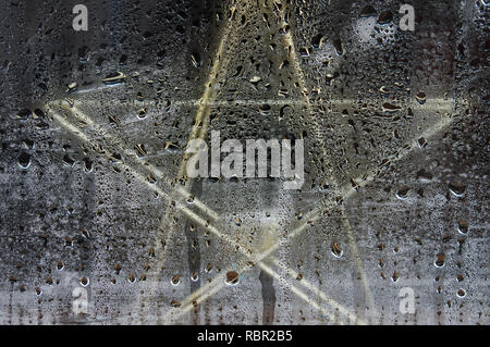 Star-shaped tealight holder behind a window covered in condensation Stock Photo