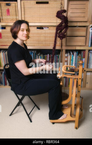 Woman spinning on a Schacht Matchless Single Treadle Upright Spinning Wheel (castle-style), using alpaca top fiber. Stock Photo