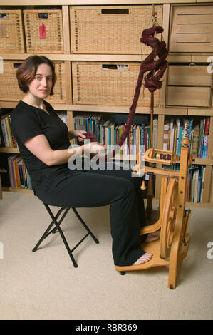 Woman spinning on a Schacht Matchless Single Treadle Upright Spinning Wheel (castle-style), using alpaca top fiber. Stock Photo