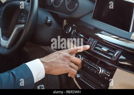 Young mulatto businessman driver sitting inside the car pushing emergency alarm button close-up Stock Photo
