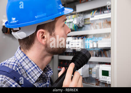Close-up Of A Electrician Examining A Fuse Box With A Torch Stock Photo