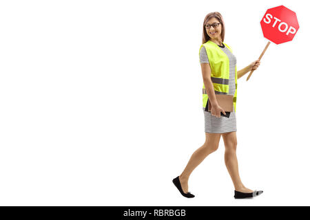 Full length shot of a young woman with safety vest and stop sign walking and looking backwards isolated on white background Stock Photo