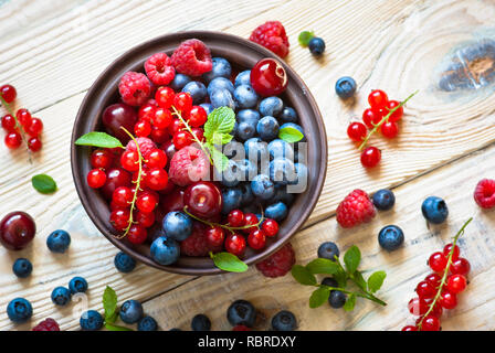 Fresh berries. Various  summer berries in a bowl on rustic wooden table. Stock Photo