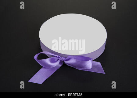 Ribbon bow around a paper lid on a black Stock Photo