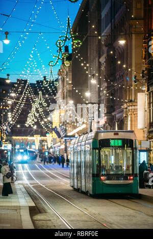 Helsinki, Finland. Tram Departs From Stop On Aleksanterinkatu Street. Night Evening Christmas Xmas New Year Festive Street Illumination. Beautiful Dec