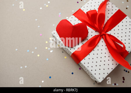 Valentines day concept with red origami paper hearts, confetti and gift box on gray background, romantic concept Stock Photo