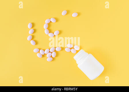 Vitamin c pills dropped from bottle on yellow background. Flat lay, top view, free copy space. Stock Photo