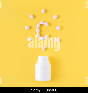 Vitamin c pills dropped from bottle on yellow background. Flat lay, top view. Stock Photo