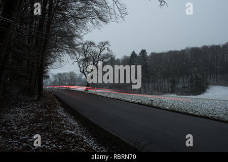wintry road with light trails from cars Stock Photo