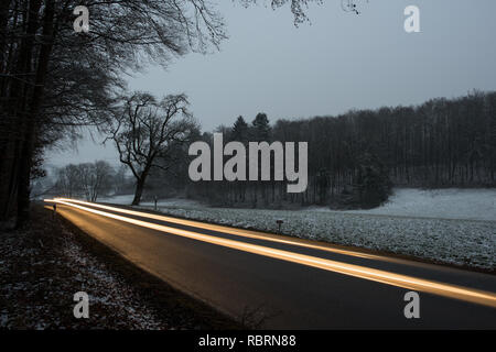 wintry road with light trails from cars Stock Photo