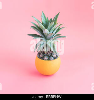 Pineapple mixing with orange on pink pastel color background. Stock Photo