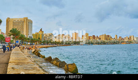 ALEXANDRIA, EGYPT - DECEMBER 19, 2017: Walk along the shore of the city with a view on urban quarters and line of palms, on December 19 in Alexandria. Stock Photo