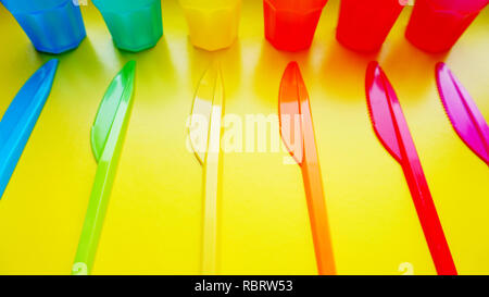 Colored plastic ware. Tableware for a picnic made of colored plastic. Knives and mug in the set of crockery for picnics, tourism and any travel. Yello Stock Photo