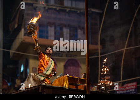 A Hindu priest or Pujari swings a burning oil lamb in prayer while carrying out the evening Ganga Aarti in Dashashwamedh Ghat, Varanasi, India Stock Photo