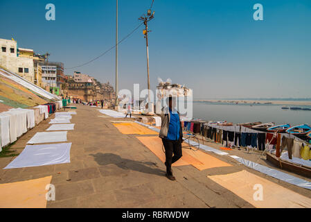 Street hawker carries his wares on this head while walking along the Ganges river in Varanasi, India Stock Photo