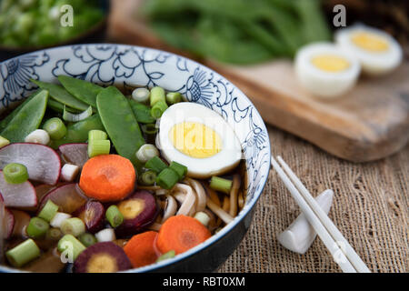 Colorful fresh bowl of udon noodle and vegetable soup with chopsticks. Stock Photo