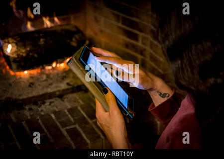 woman is playing with her tablet in front of a fireplacce Stock Photo