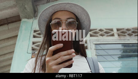 Stylish female using smartphone near shabby building Stock Photo
