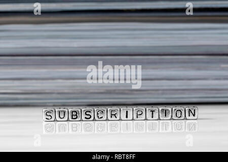 Subscription on beads with magazines stacked in the background reflected on a white surface Stock Photo