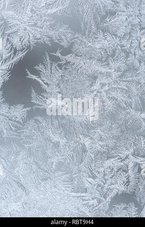 Abstract frosty pattern on window glass, close up. Winter holiday vertical background