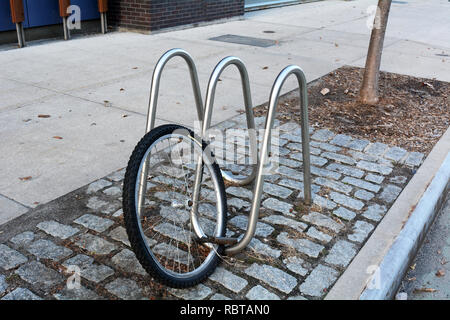 Bicycle Wheel of Stolen Bike Left On Sidewalk Bike Rack In Brooklyn Stock Photo