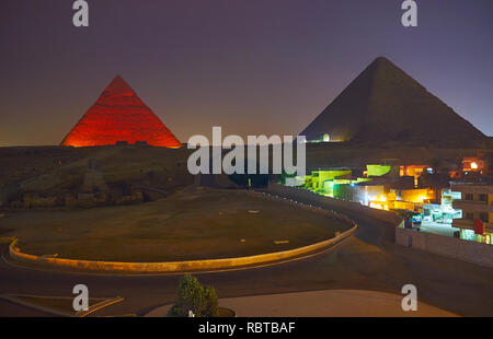 The brightly illuminated Great Pyramids in Necropolis of Giza on dark cloudy evening, Egypt. Stock Photo