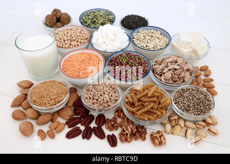 Health food for vegans with tofu bean curd, legumes, pasta, grains, cereals, nuts, seeds, almond milk, butter and yoghurt. Stock Photo
