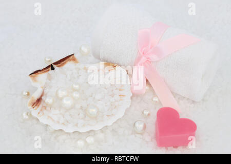 Sea salt for skincare exfoliation beauty treatment in a scallop shell with white flannel, heart shaped soap and pearls. Health care concept, top view. Stock Photo